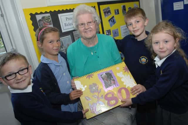 NAPB 1505143AM1 Summerbridge lollipop lady. Summerbridge Primary School lollipop lady Mary Fisher is presented with a book of photos to celebrate her 80th. birthday by Fin Burton(5), Imogen Carrington(6), Matthew Fazal(6) and Lily Glover(6). (1505143AM1)