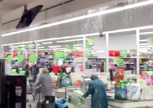 Shoppers were left stranded in an ASDA supermarket for over half an hour after rainwater burst through the roof and gushed into the aisles.  Picture: SWNS