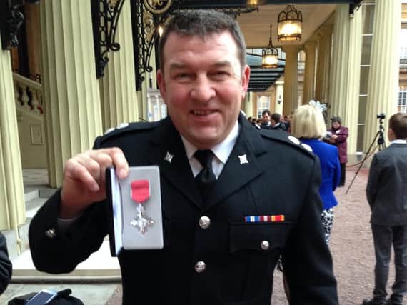 Firefighter Bruce Reid with his MBE at Buckingham Palace.