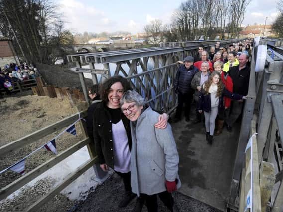 Barbara (right) and Chrissie Wilson, a mother and daughter who live on opposite sides of the River Wharfe in Tadcaster, make their first crossing over a temporary footbridge which was built following the collapse of the main bridge after severe flooding. John Giles/PA Wire