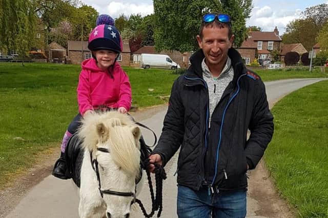 Emily with dad Jon as she rides her pony. Picture: Hannah Caffrey
