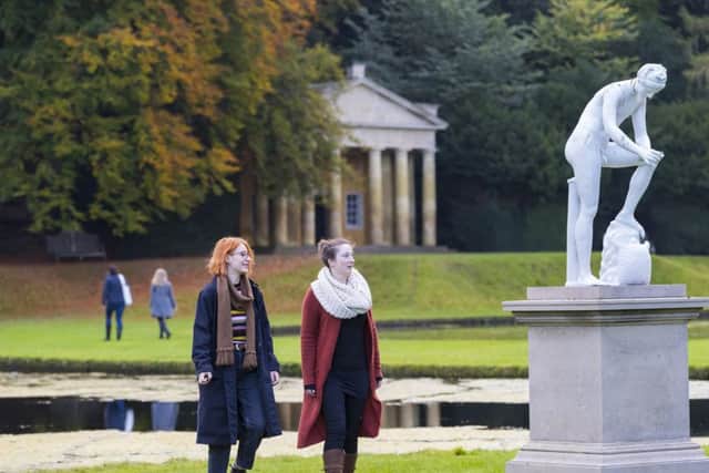 Visitors exploring the autumnal gardens at Fountains Abbey and Studley Royal Water Garden, North Yorkshire