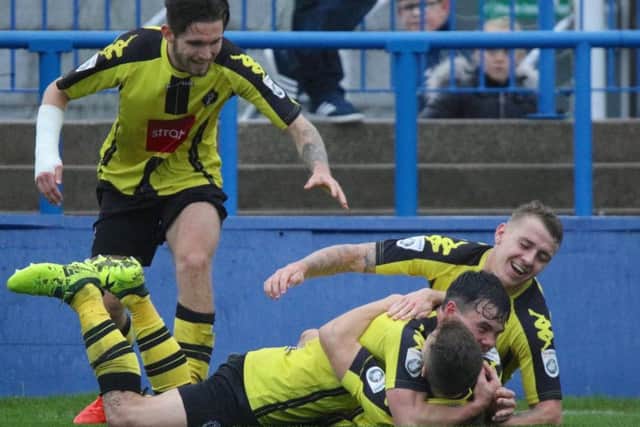 Mitch Curry, bottom, takes the congratulations of his team-mates after netting a late winner at Curzon Ashton. Picture: Town Pix