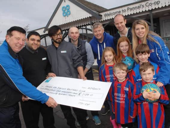 President of Pannal Ash Football JFC Cliff Trotter accepts a cheque to the value of 2189.11 from Abdul Azam  (asst. manager) and Mehraz Jamil (custormer assistant) of Pannal Co-op (1712022AM1)
