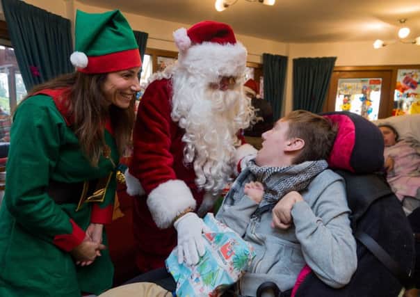 Date: 11th December 2017.
Picture James Hardisty.
Youngsters who attend the Martin House Hospice in Boston Spa, near Wetherby, had a special visit from Santa, who arrived in a helicopter with his helper's thanks to Yorkshire private aviation company Multiflight. Pictured Santa, along with Emmerdale star Gaynor Faye, handing out a present to Mikey Whalley, 20.