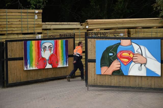 A man walks by artworks by artist Rachel List paying tribute to NHS staff battling the COVID-19 outbreak on the gates of a fencing company's premises in Pontefract (Photo by OLI SCARFF/AFP via Getty Images)